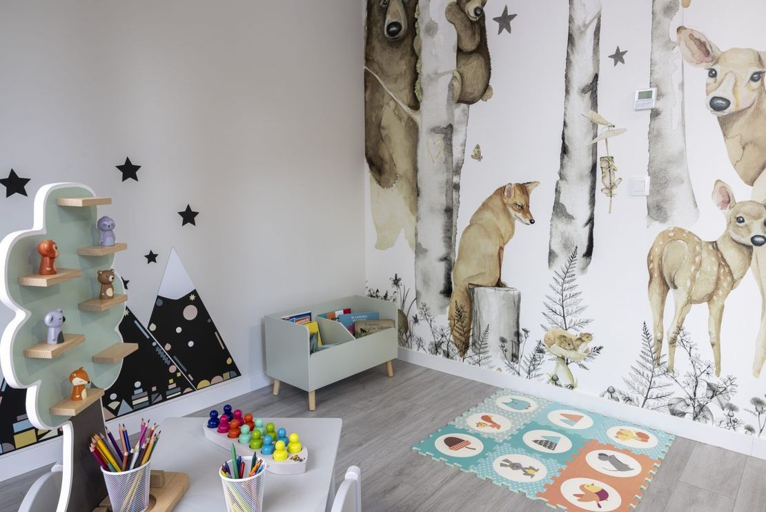 Una habitación infantil con un mural de animales en la pared.