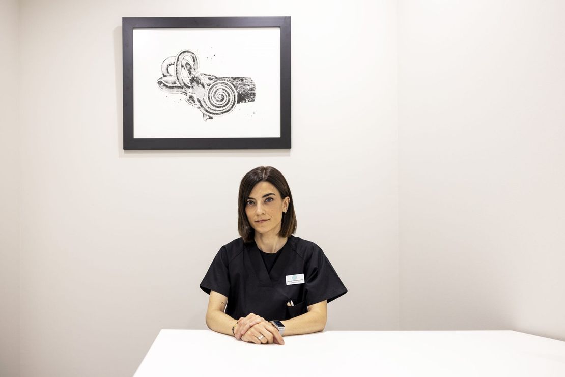 Una mujer está sentada en una mesa frente a un cuadro en la pared.