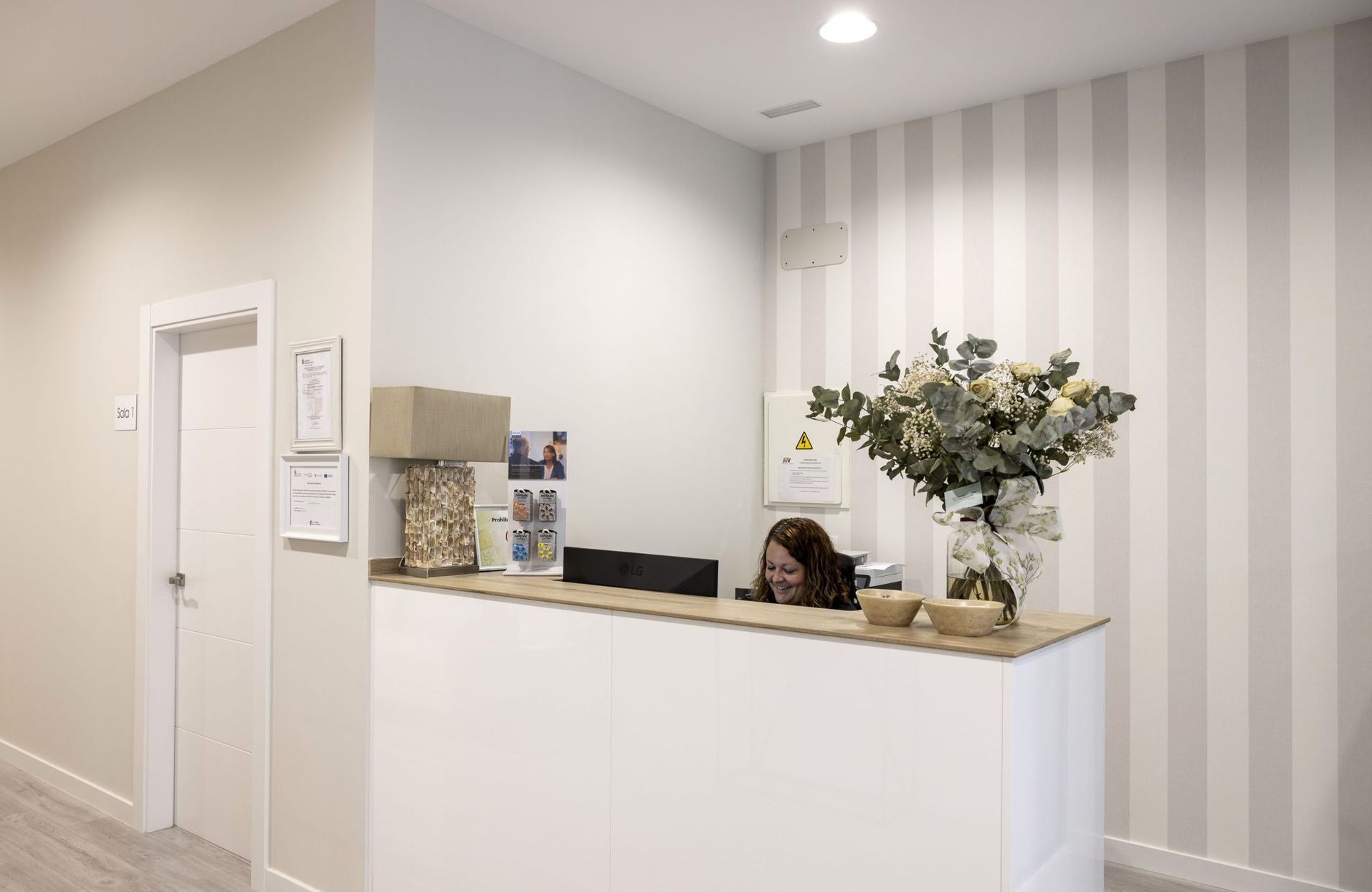 Una mujer está sentada en un mostrador de recepción en un pasillo.