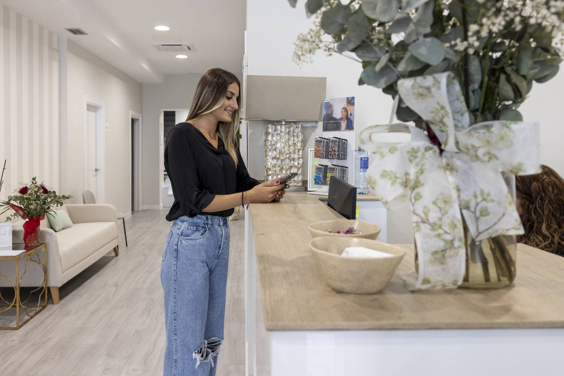 Una mujer está parada frente a un mostrador en una habitación mirando su teléfono.