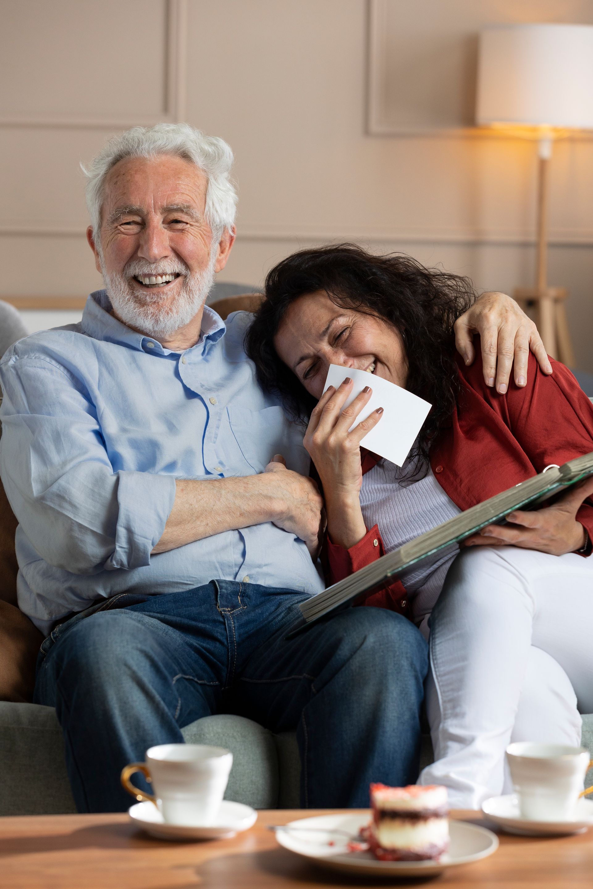 Una pareja de ancianos está sentada en un sofá leyendo un libro juntos.