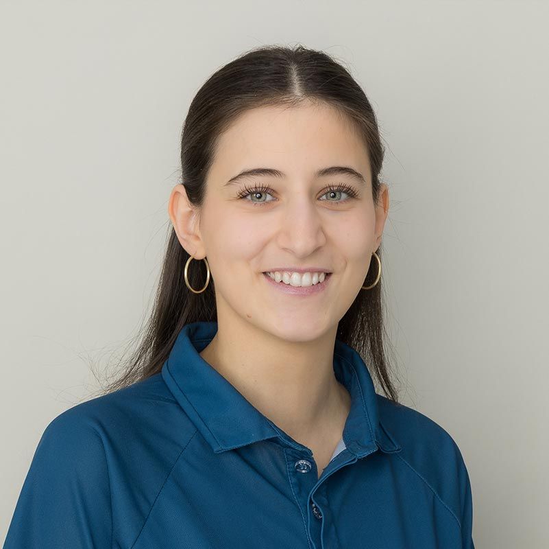 Person in einem blauen Poloshirt lächelt vor einem einfarbigen hellen Hintergrund