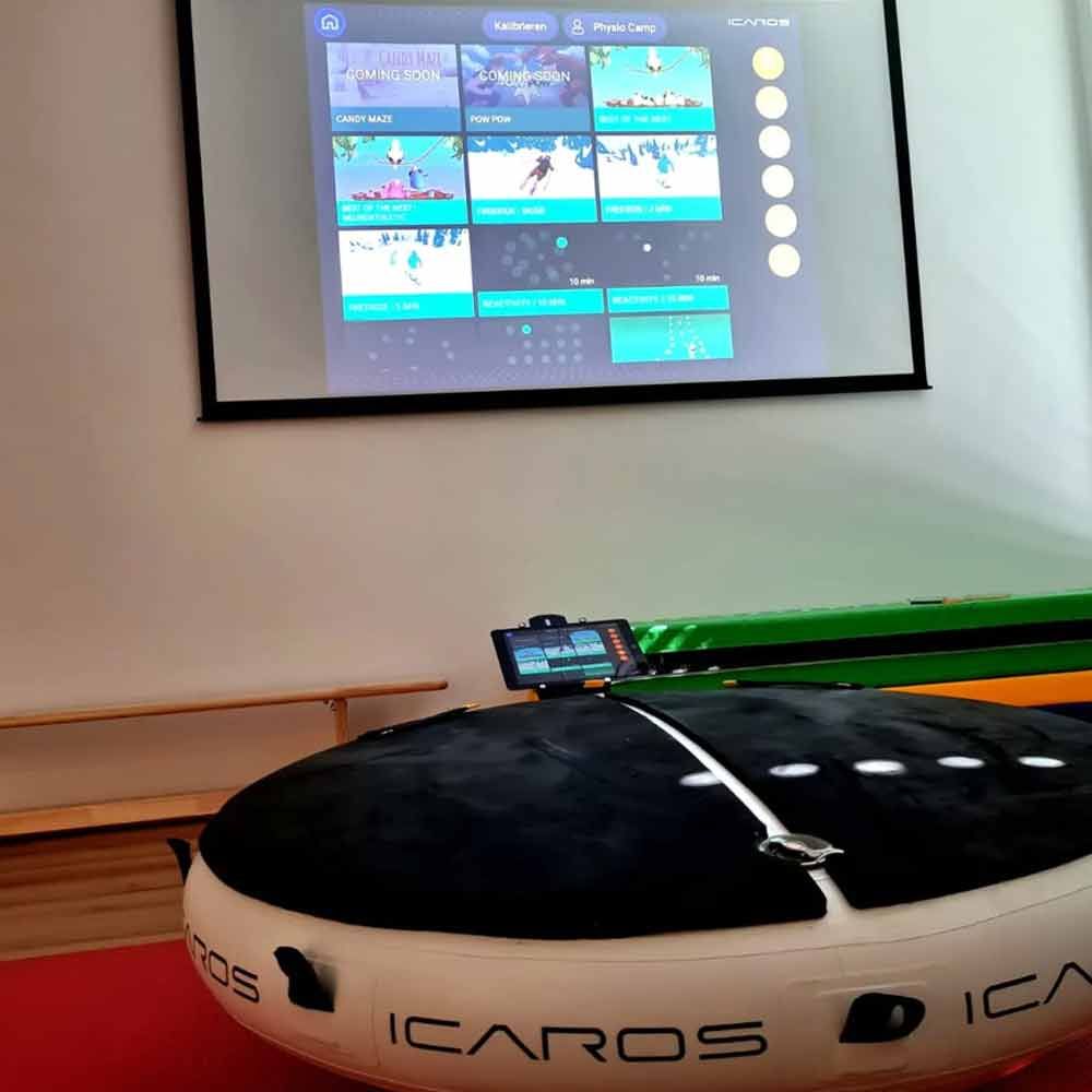 ICAROS-Trainingsgerät in einem Raum mit einem an die Wand projizierten Spielbildschirm.