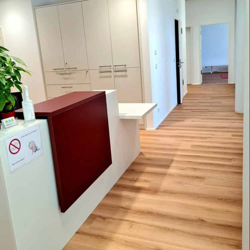 Heller Empfangsbereich mit weißen Schränken und ein langer Flur mit Holzboden