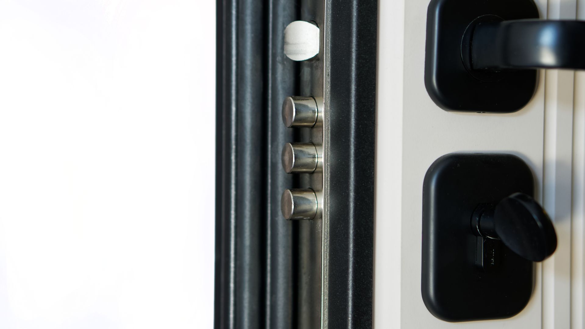 Gros plan sur une porte de sécurité équipée d’une serrure multipoint avec plusieurs pênes de verrouillage apparents.