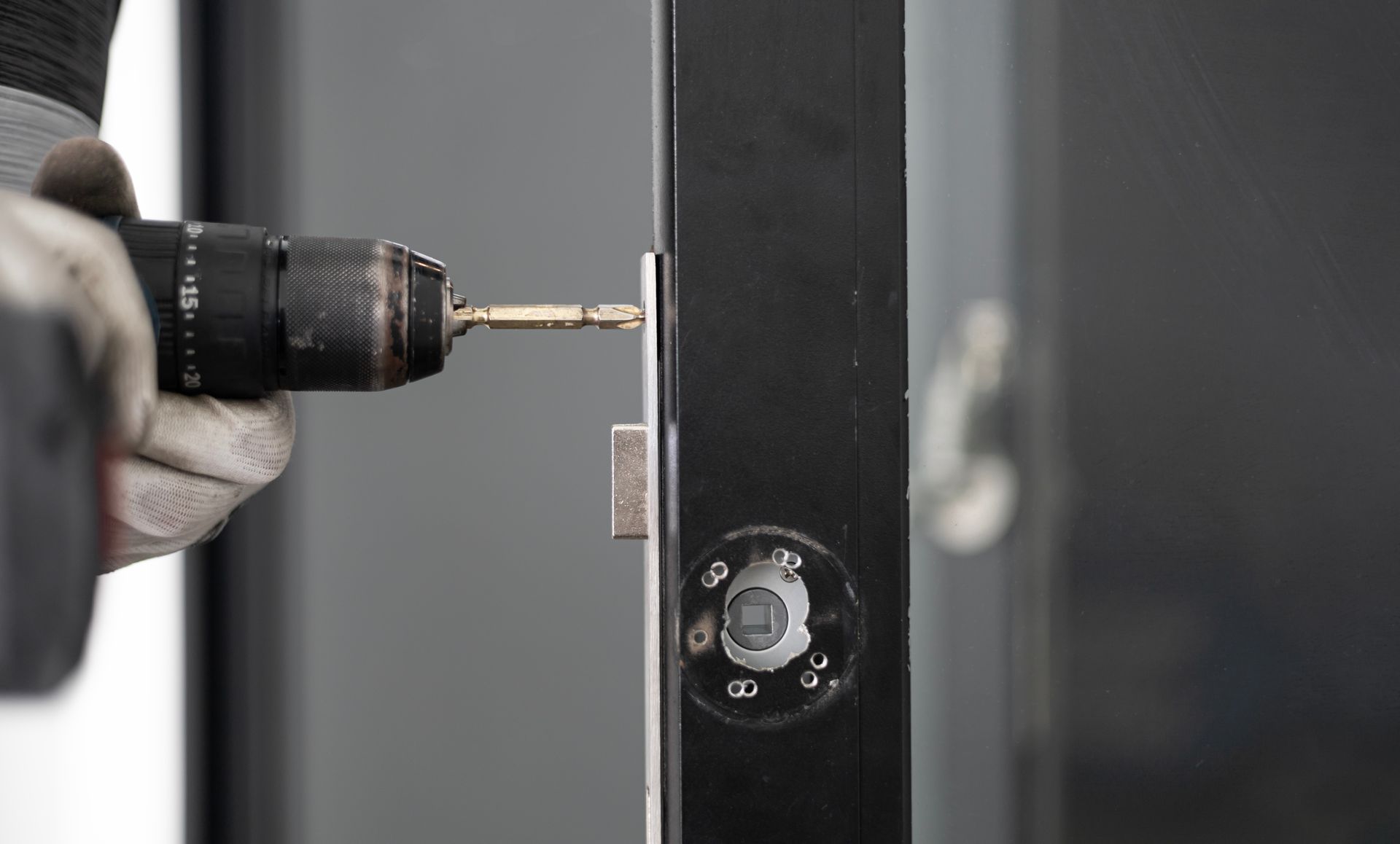 Installation d’une serrure sur une porte métallique à l’aide d’une perceuse-visseuse.