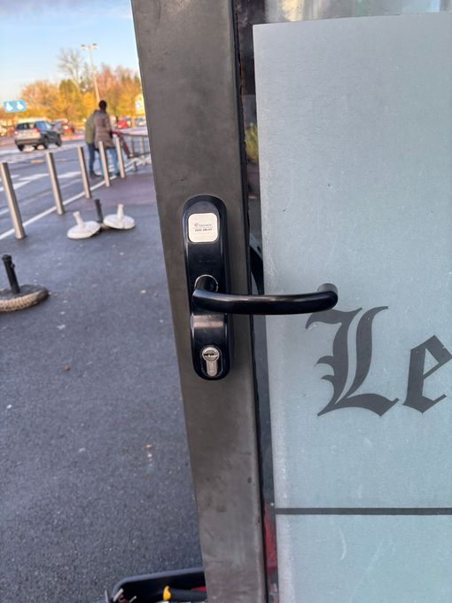 Porte vitrée de commerce équipée d’une serrure de sécurité et d’une poignée noire.