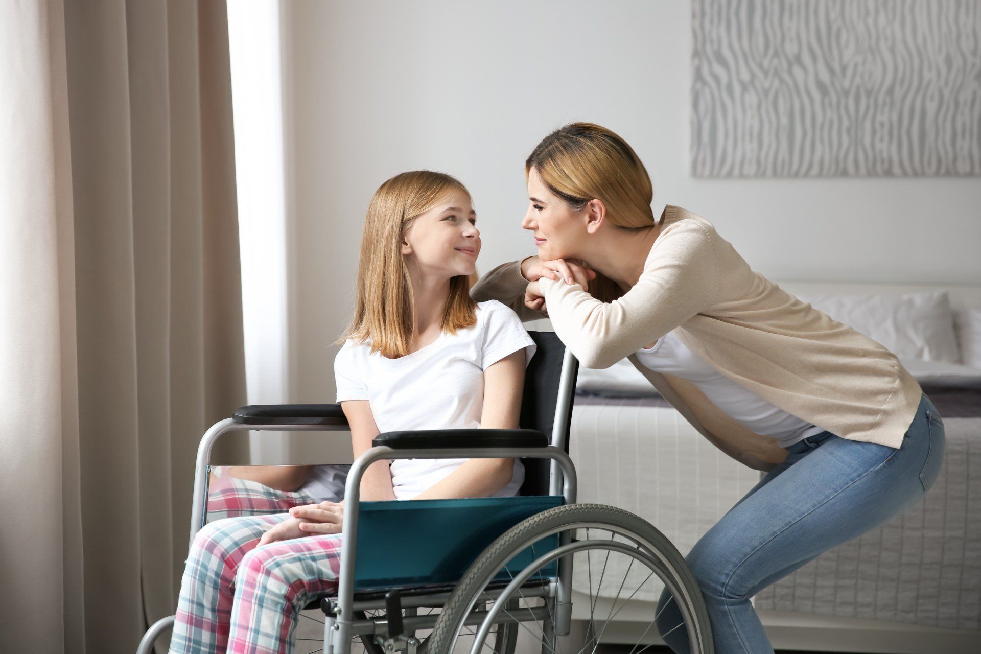 Femme souriant à une fillette en fauteuil roulant
