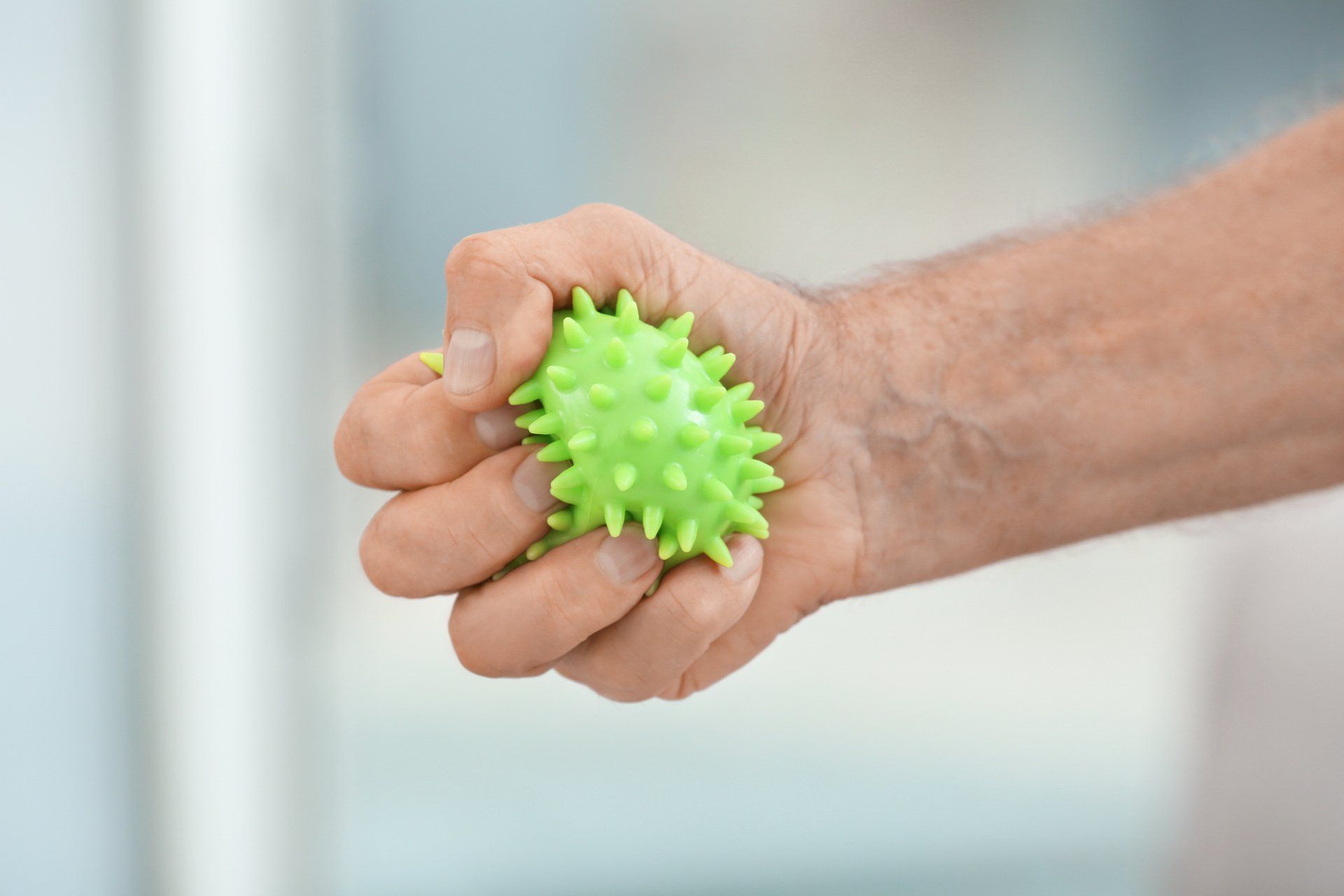 Main fermée sur une boule de rééducation verte fluo