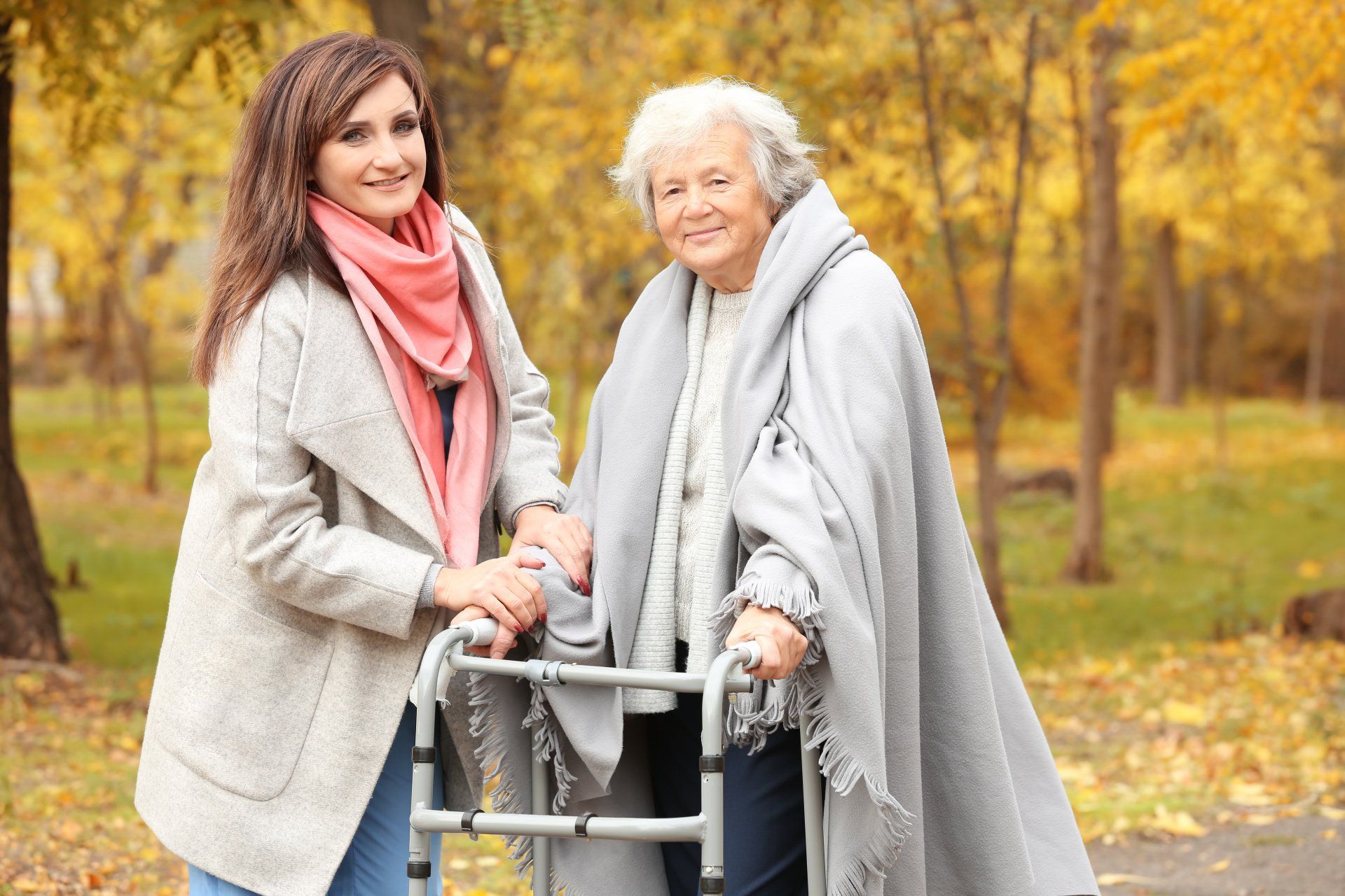 Femme âgée en déambulateur accompagnée d'une jeune femme