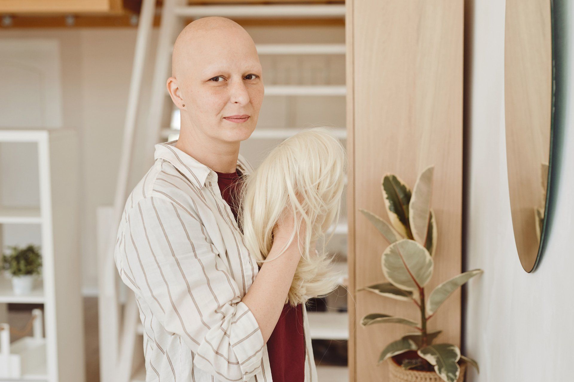 Femme jeune chauve avec une perruque blonde dans la main
