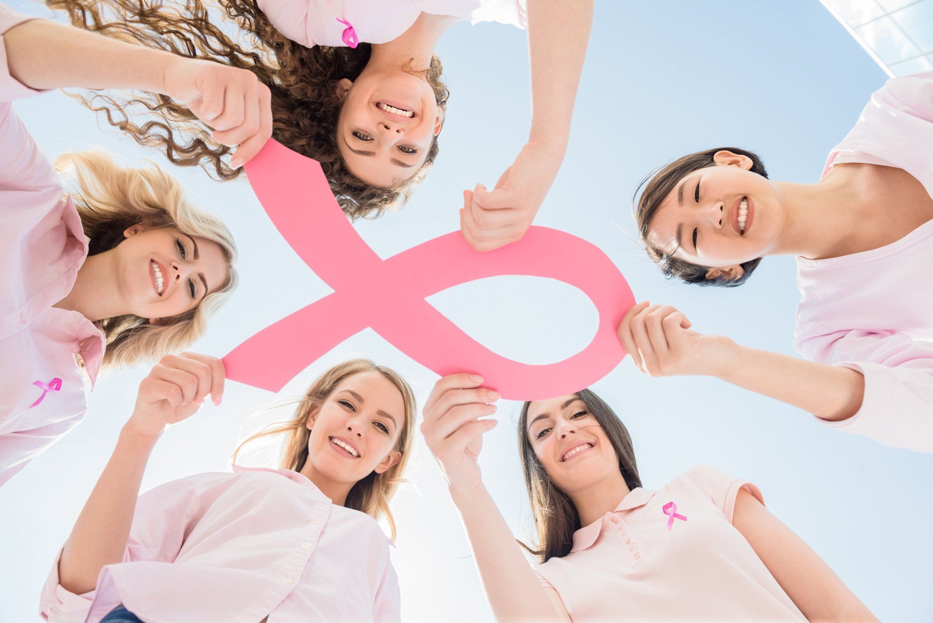 Cinq femmes tenant d'une main un gros noeud rose