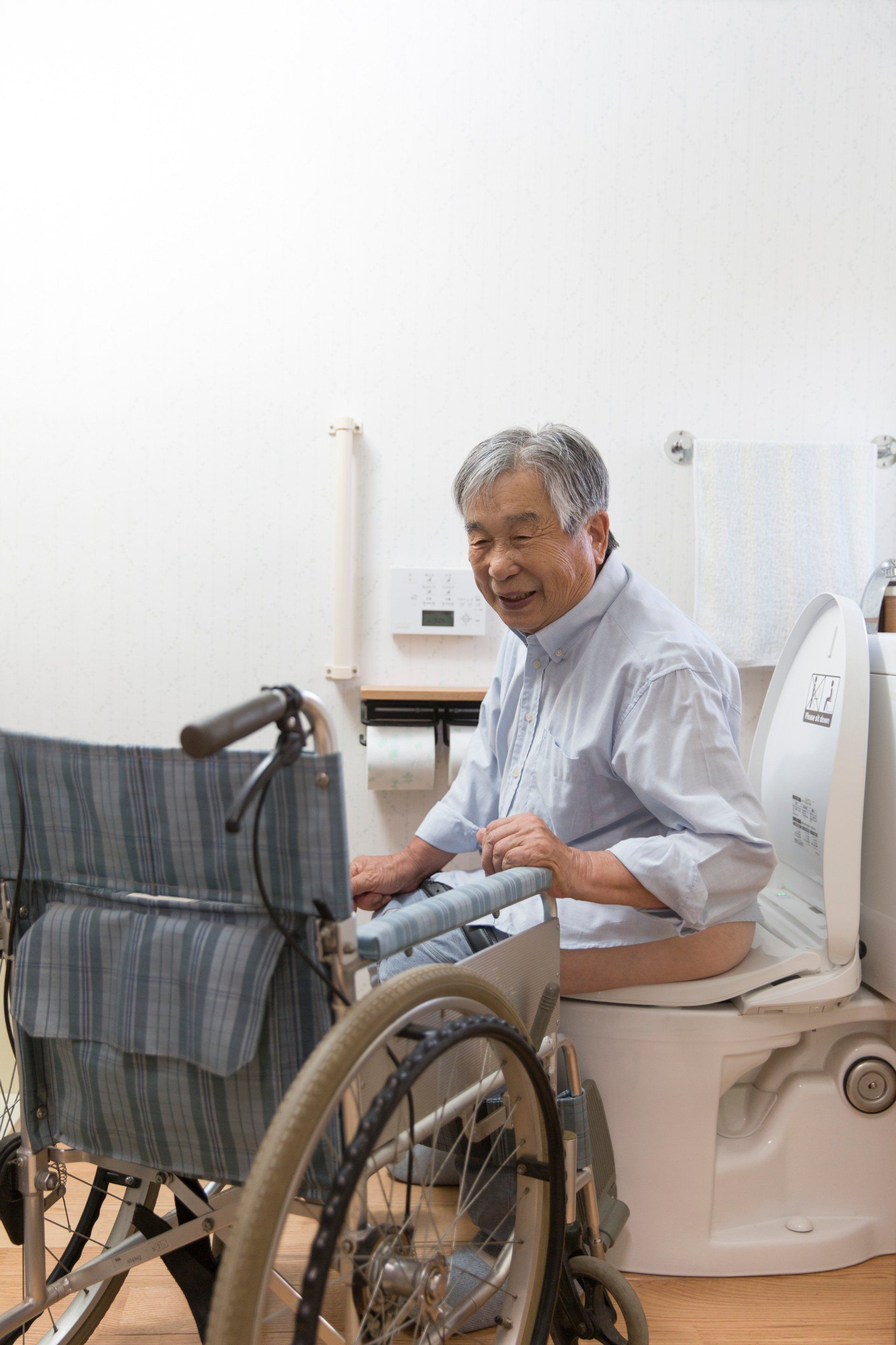 Homme en fauteuil roulant sur un siège WC