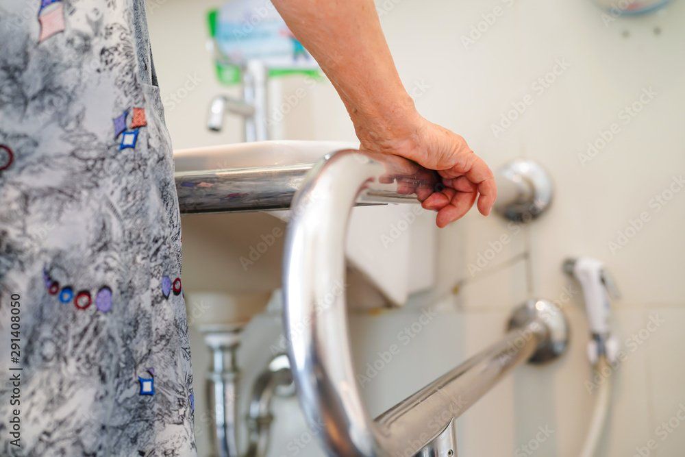 Dame âgée qui s'appuie sur barre et lavabo