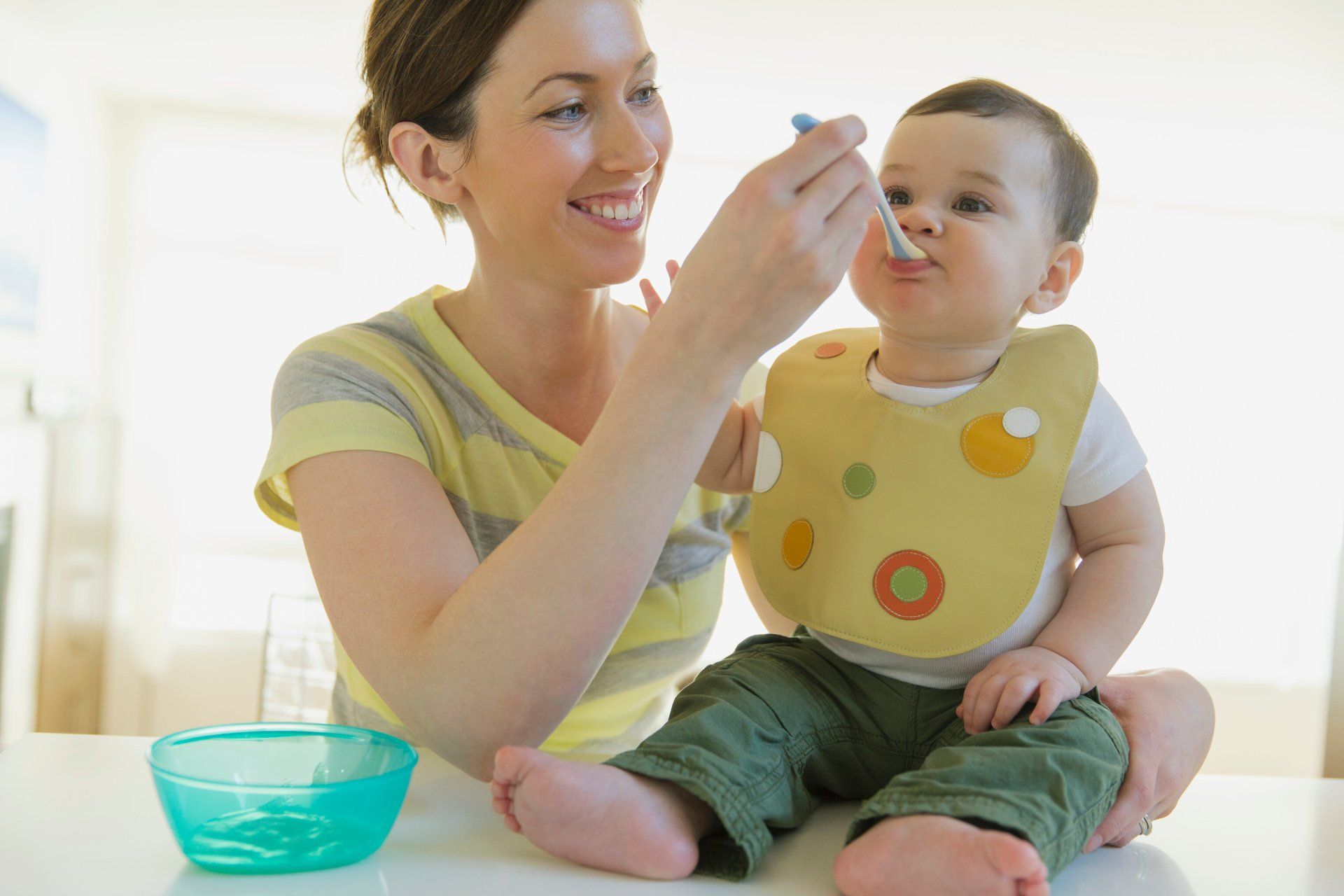 Maman donnant à manger à un bébé avec un bavoir jaune