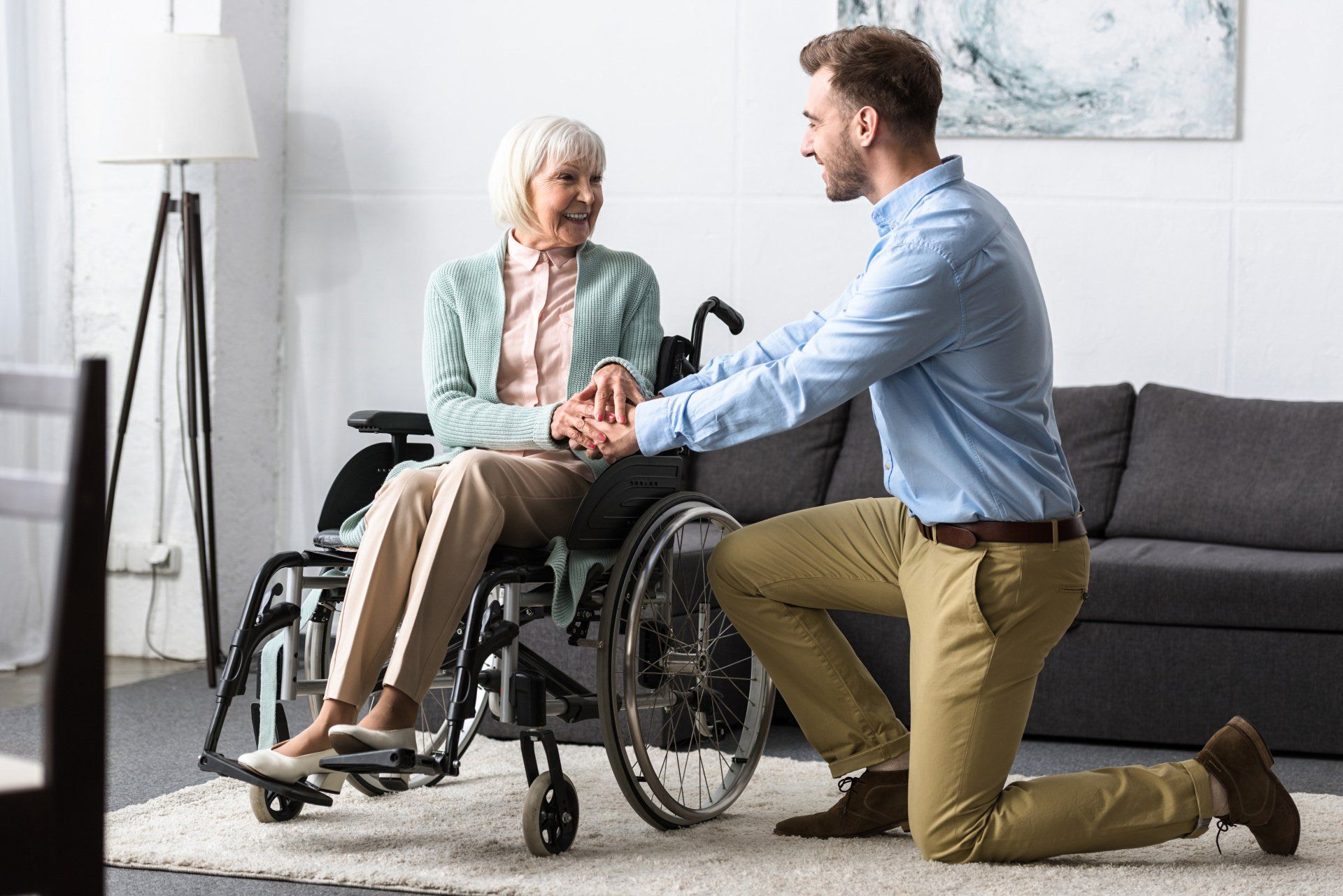 Femme âgée en fauteuil roulant avec homme jeune à genou