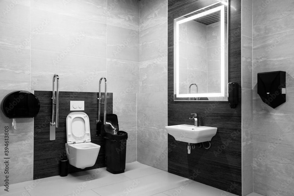 Toilettes aménagées avec barres de soutien, moderne fond gris et noir