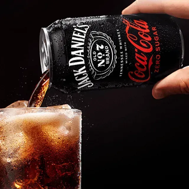 Una persona está vertiendo una lata de Jack Daniels en un vaso.