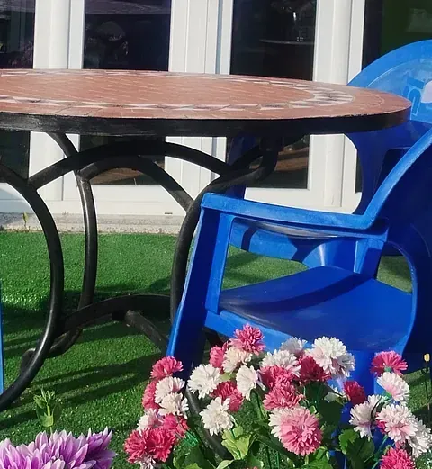 Una mesa y sillas con flores delante de ellas.