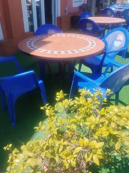 Una mesa redonda con sillas azules frente a un edificio.