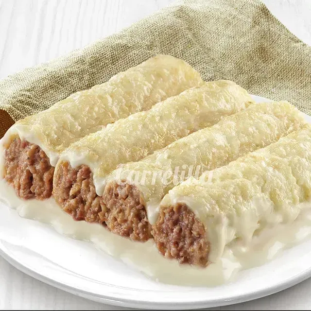 Un plato blanco cubierto con canelones con carne y salsa.