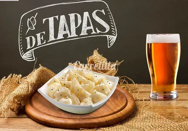 Un plato de comida y un vaso de cerveza sobre una mesa de madera.