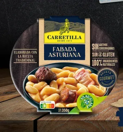 Un paquete de fabada asturiana reposa sobre una mesa de madera.