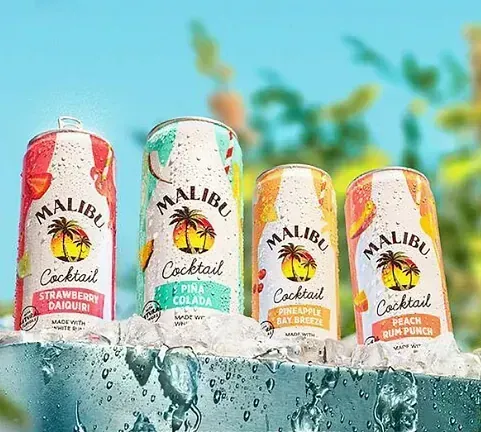 Cuatro latas de cócteles Malibu están sobre hielo.