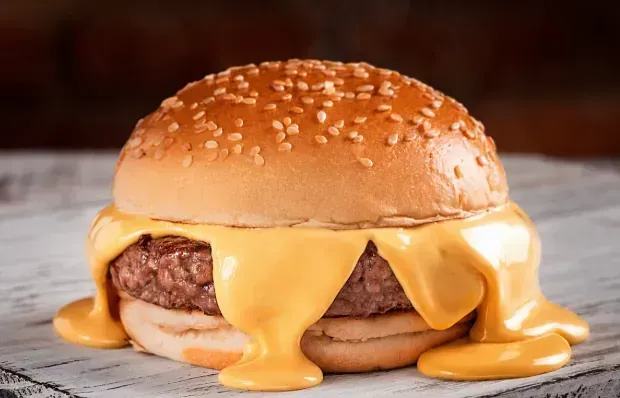 Un primer plano de una hamburguesa con queso sobre un pan sobre una mesa.