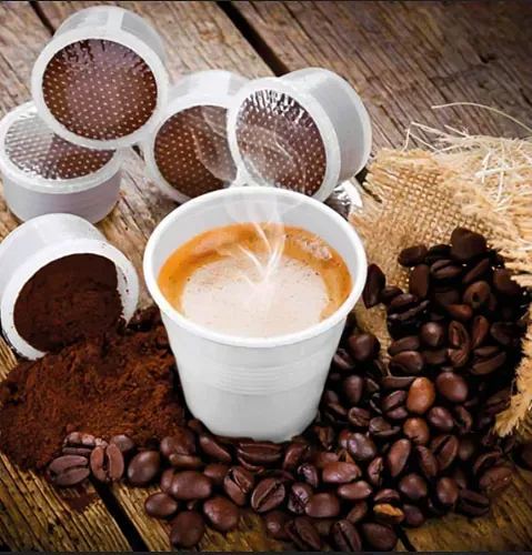 Una taza de café rodeada de granos de café y cápsulas de café.