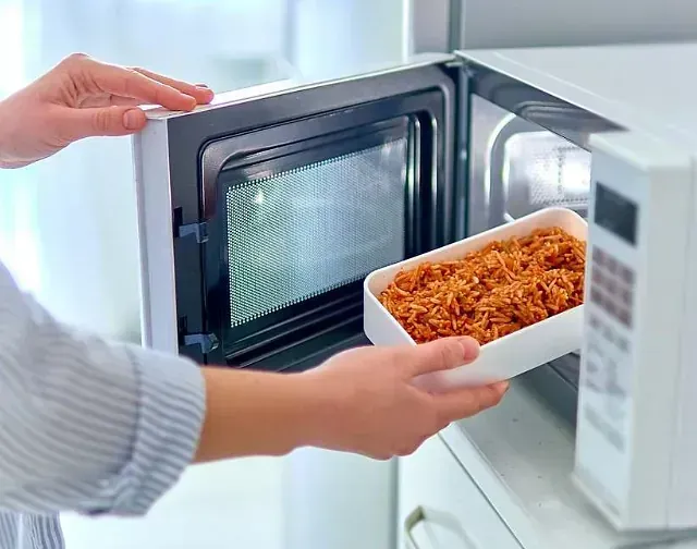 Una persona está poniendo comida en un horno microondas.