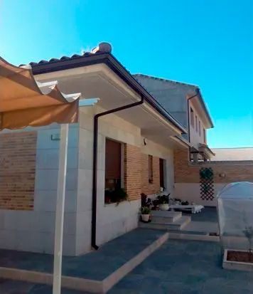 Una casa con un techo que tiene un canalón y una sombrilla delante.