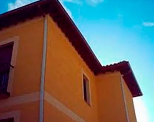 Una casa amarilla con un cielo azul al fondo.