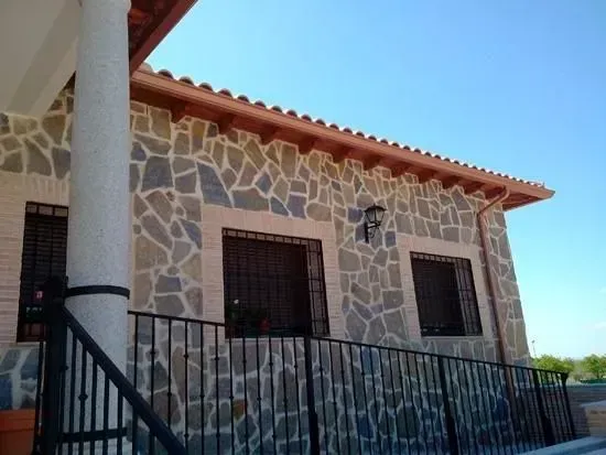 Una casa de piedra con una valla de hierro forjado a su alrededor