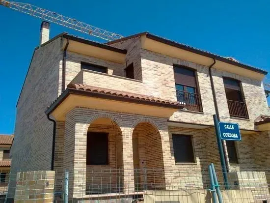 Una casa de ladrillo en construcción con una grúa al fondo.