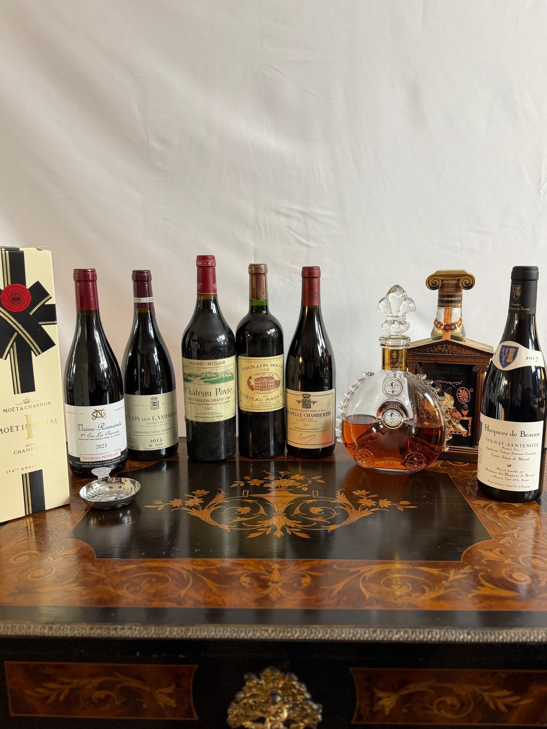 Bouteilles de vin et de spiritueux disposées sur une surface décorative en bois, sur fond blanc.