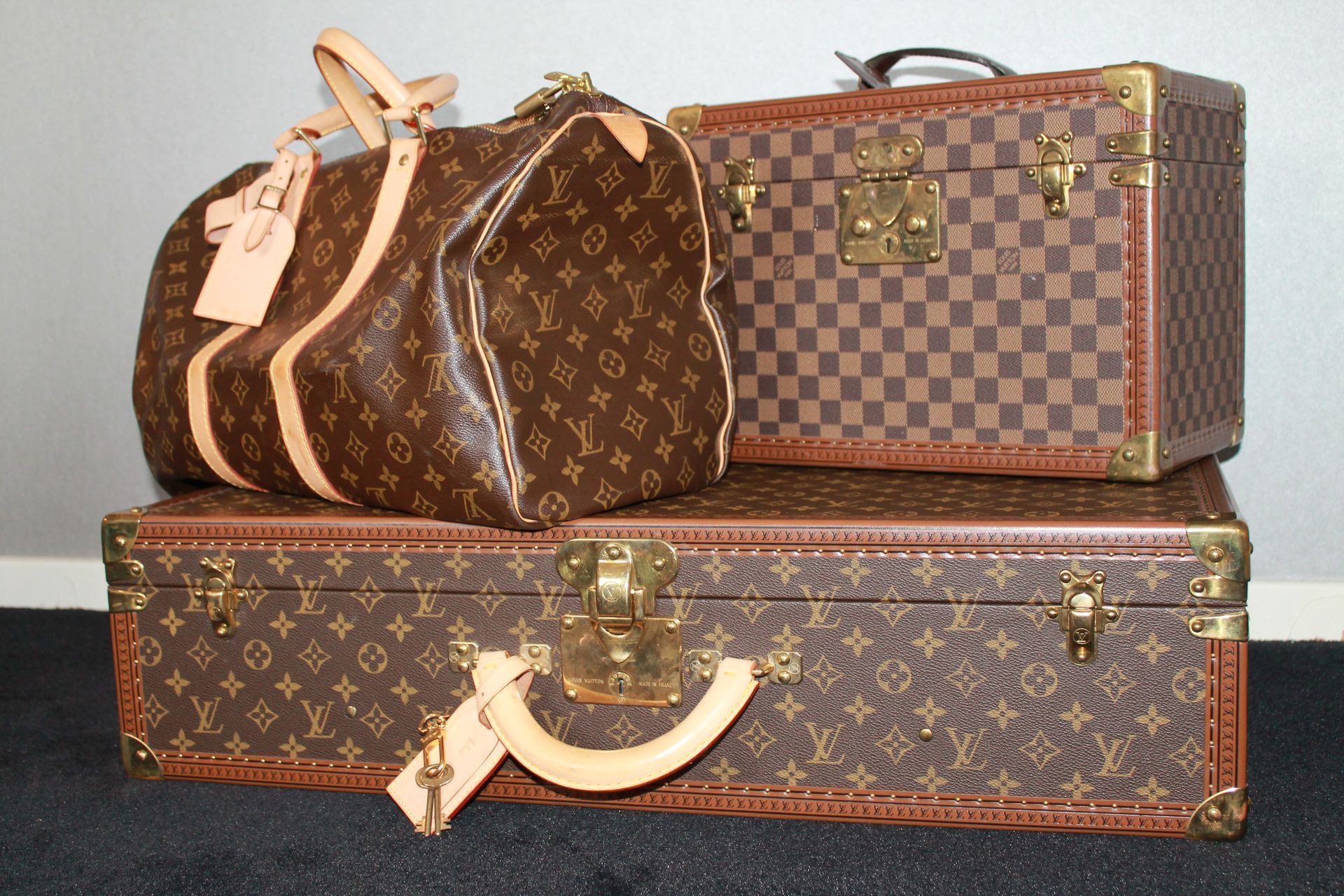 Quatre valises Louis Vuitton marron, de tailles différentes, empilées.