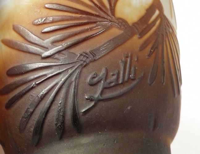 Gros plan sur un vase en verre brun orné d'un motif de bambou sculpté et portant la signature « Gallé ».