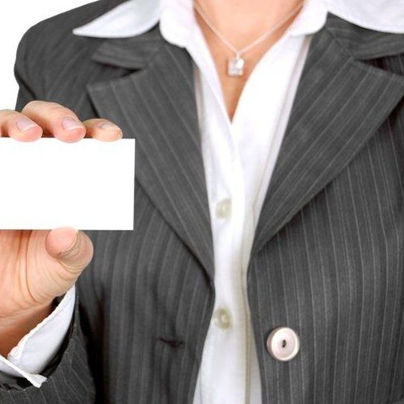 Mujer con traje sosteniendo una tarjeta de visita en blanco.