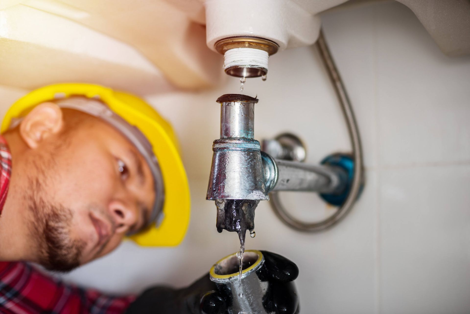 Un fontanero está arreglando una tubería del lavabo de un baño.