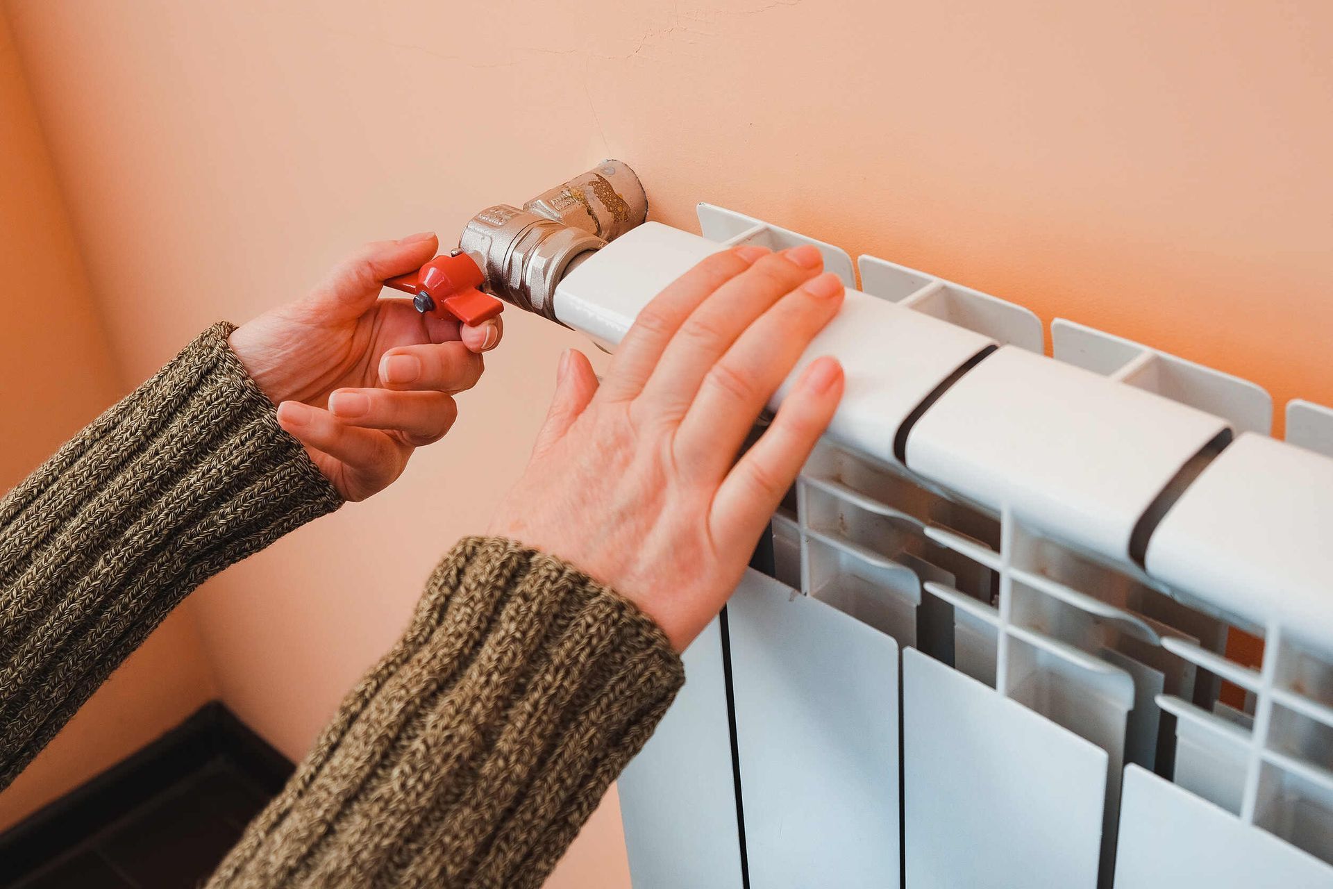 Una persona está ajustando un radiador con un destornillador.
