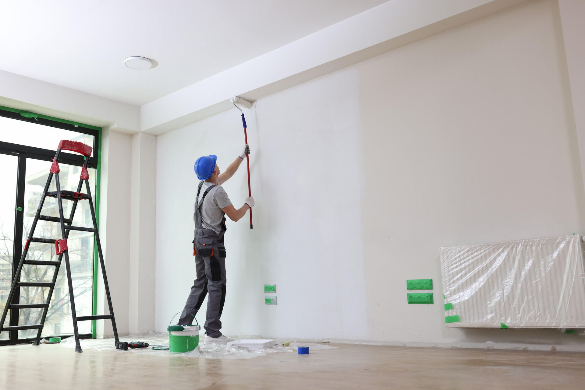 Un hombre está pintando una pared con un rodillo en una habitación vacía.