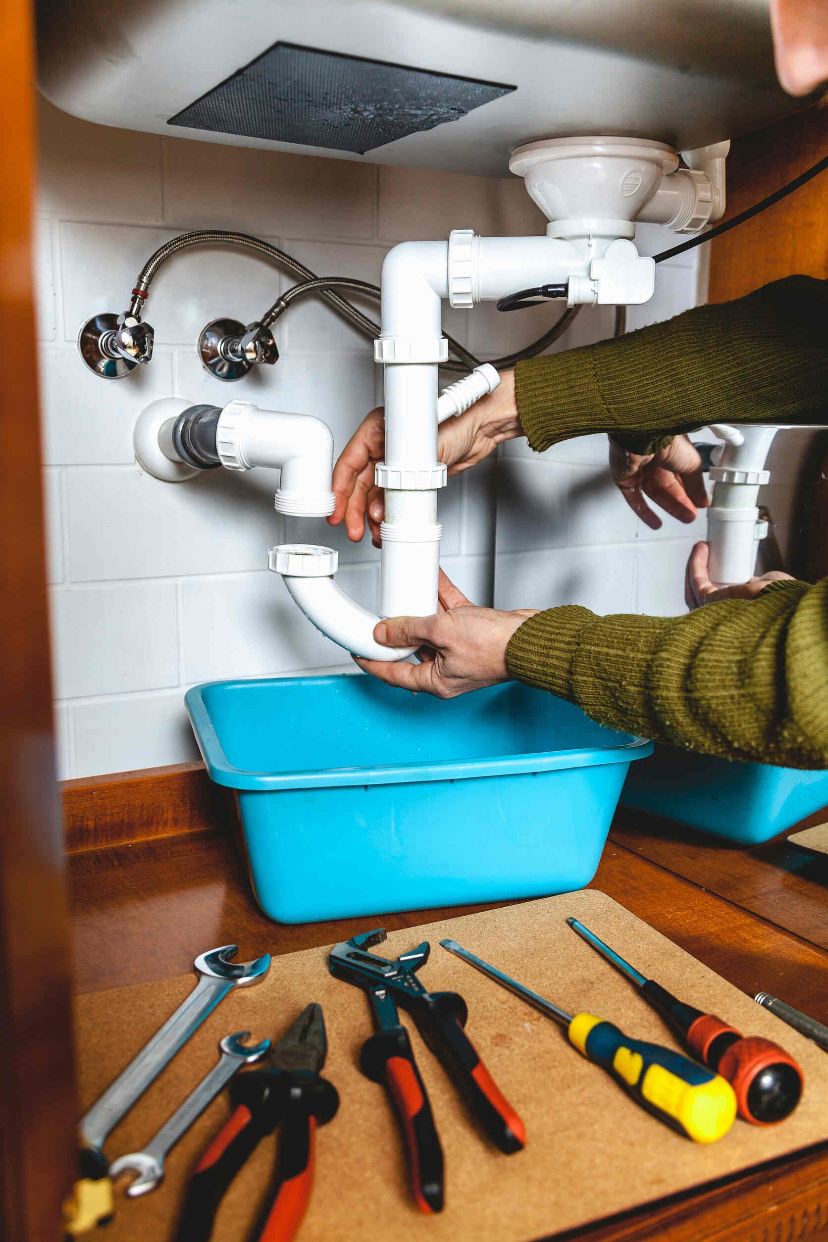 Un fontanero está arreglando un fregadero en una cocina.