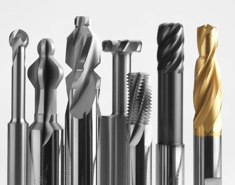 Un grupo de brocas están alineadas en fila sobre una superficie blanca.