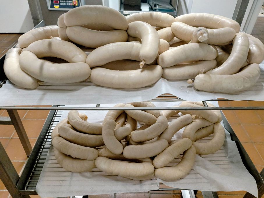 Des côtelettes de porc crues sur une planche à découper en bois, garnies de persil, sur une table sombre.