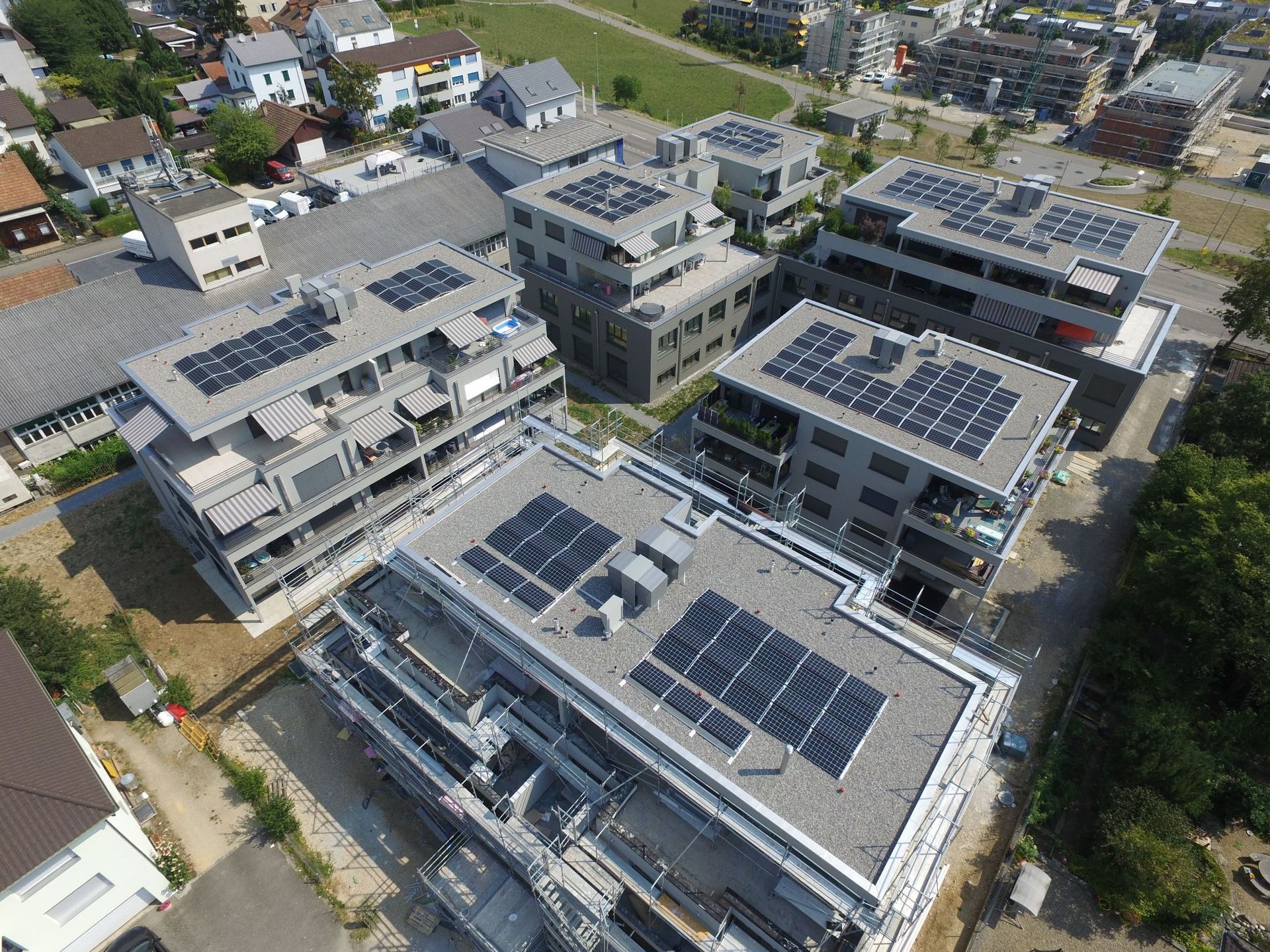Luftaufnahme moderner Wohnhäuser mit Solarmodulen auf den Dächern.