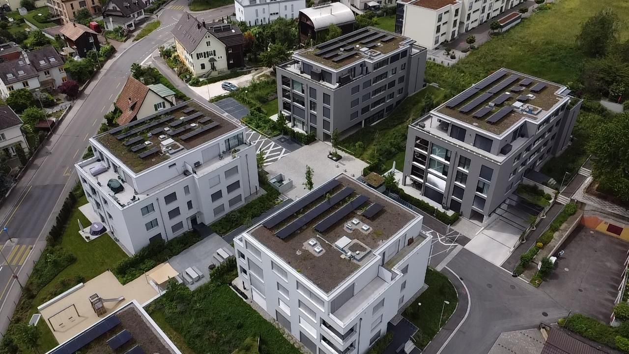 Luftaufnahme mehrerer moderner Wohnhäuser mit Solarmodulen auf den Dächern.