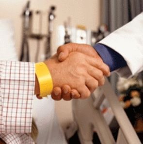 Um homem com uma pulseira amarela aperta a mão de um médico