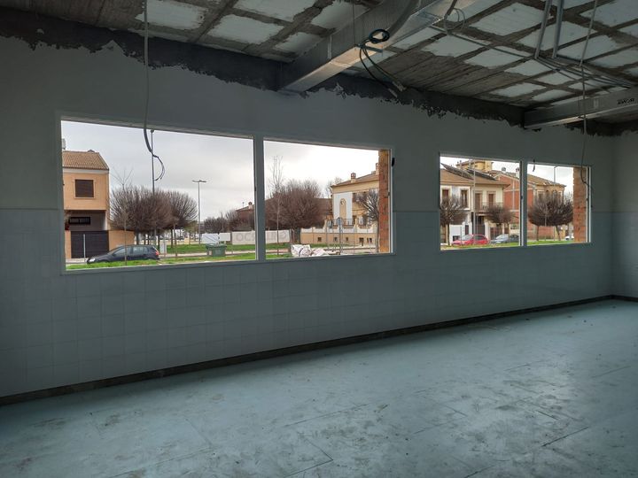 Una habitación vacía con muchas ventanas y vista a una calle.