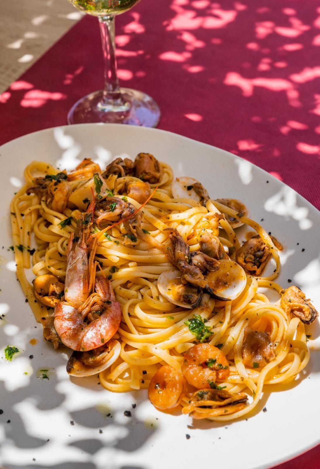 Pasta con camarones y mariscos en un plato blanco con una copa de vino, vista aérea.